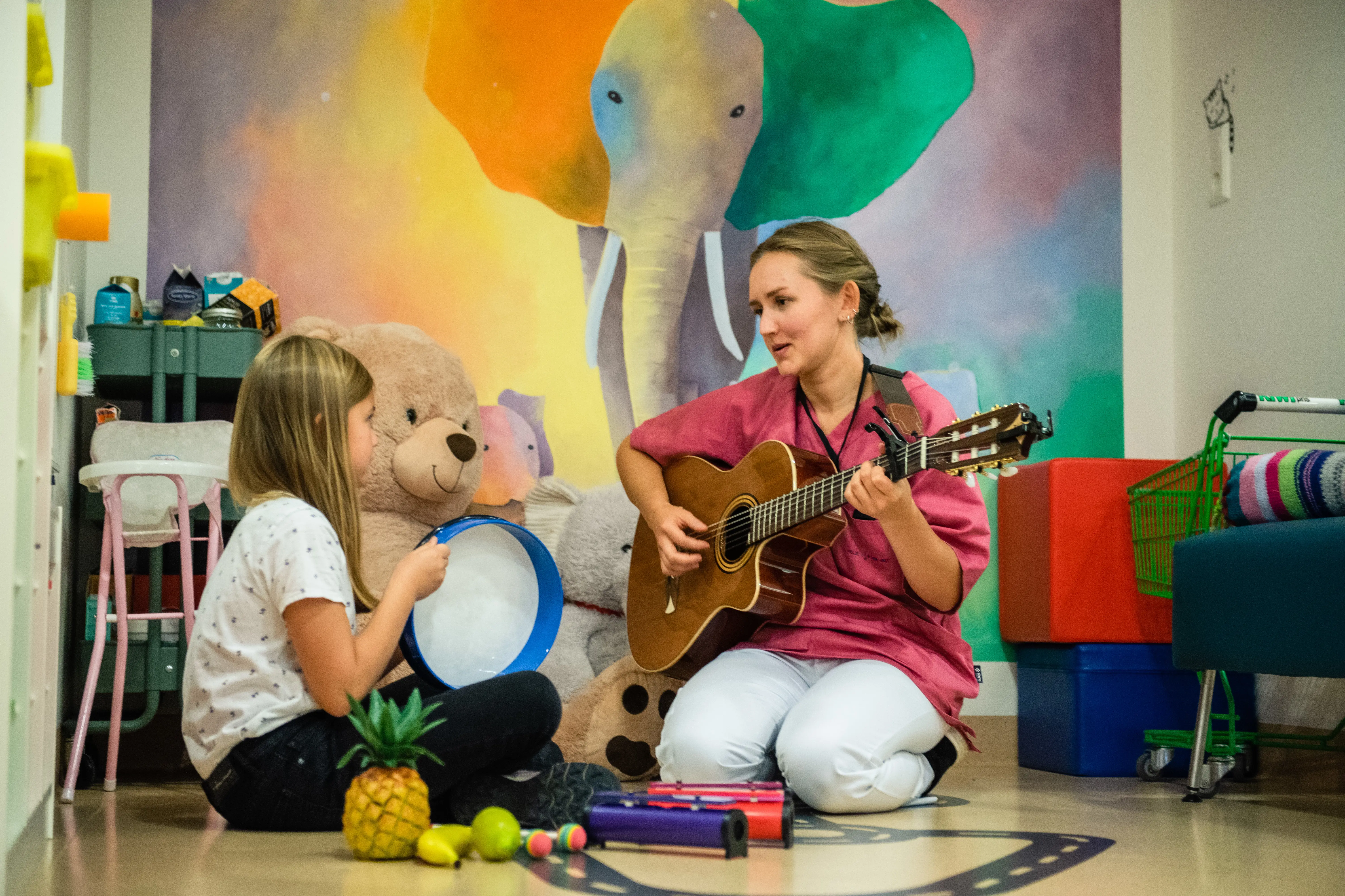 Barn spiller instrument sammen med musikkterapeut som spiller gitar.
