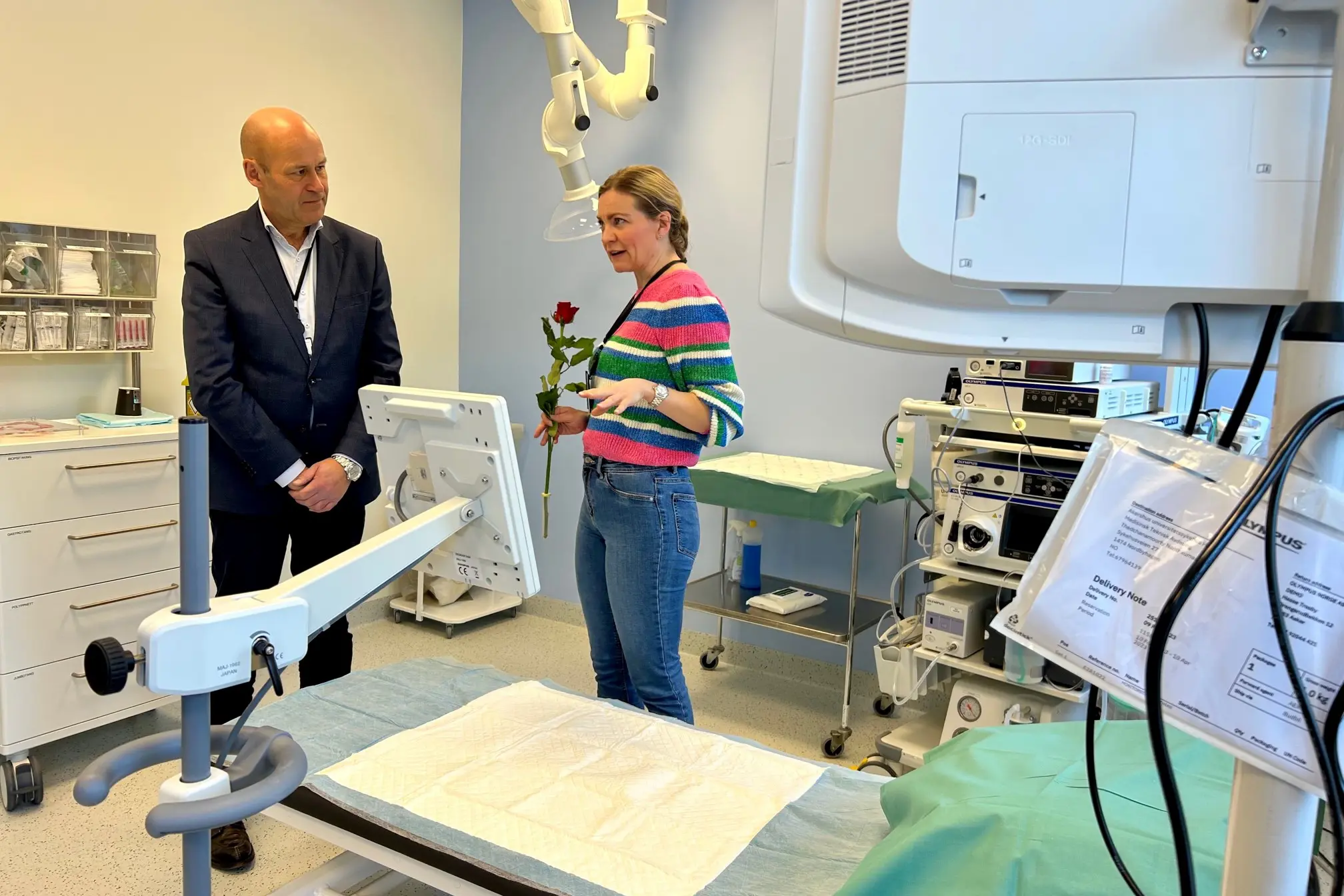 Direktør oi dress og overlege i fargerik genser på behandlingsrom