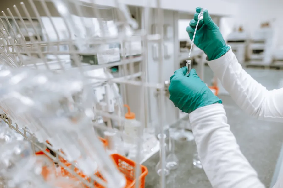 Hanskekledt tekniker i hvitt tester legemiddel i laboratorium
