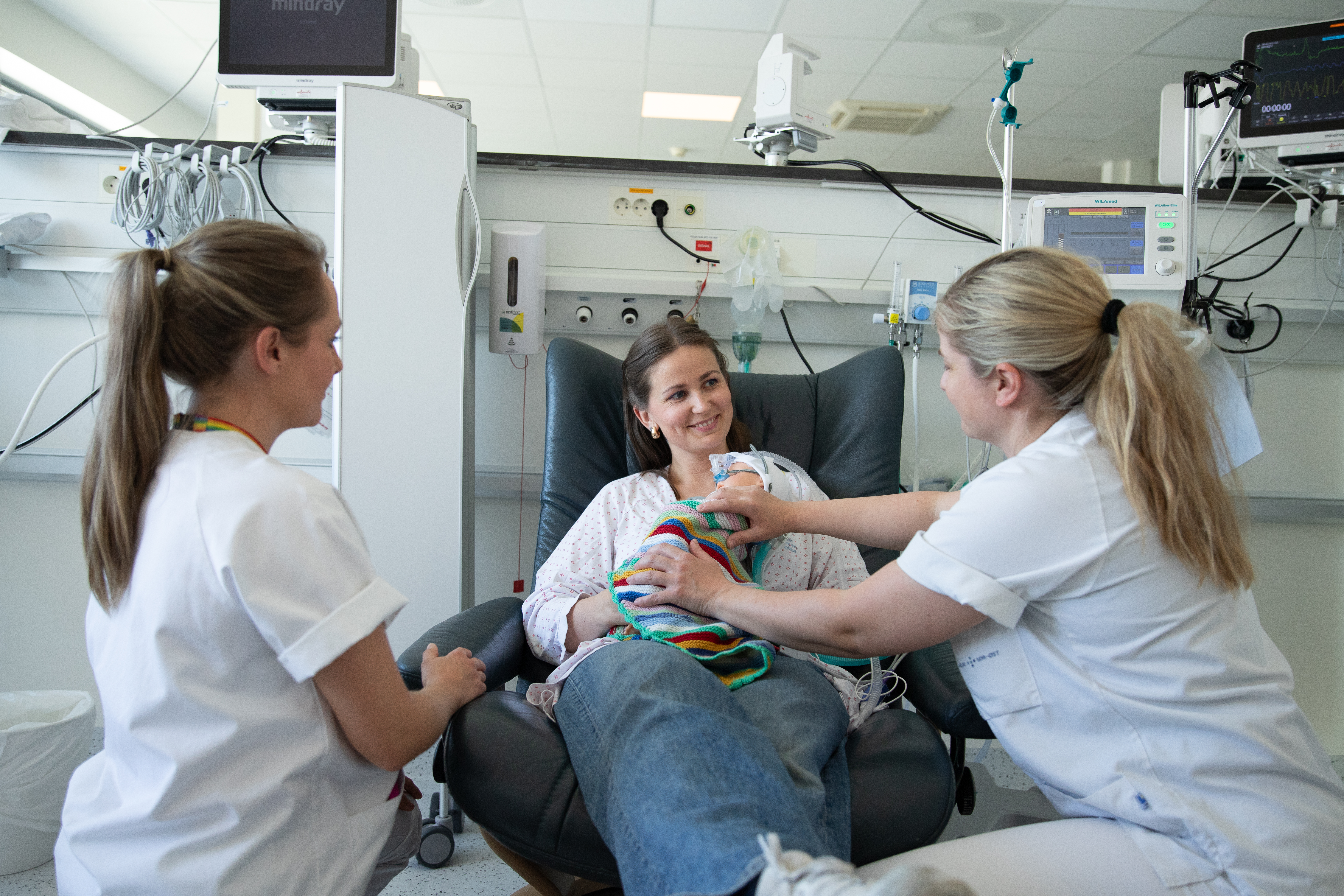 helsepersonell i samtale med forelder som har et nyfødt barn på brystet