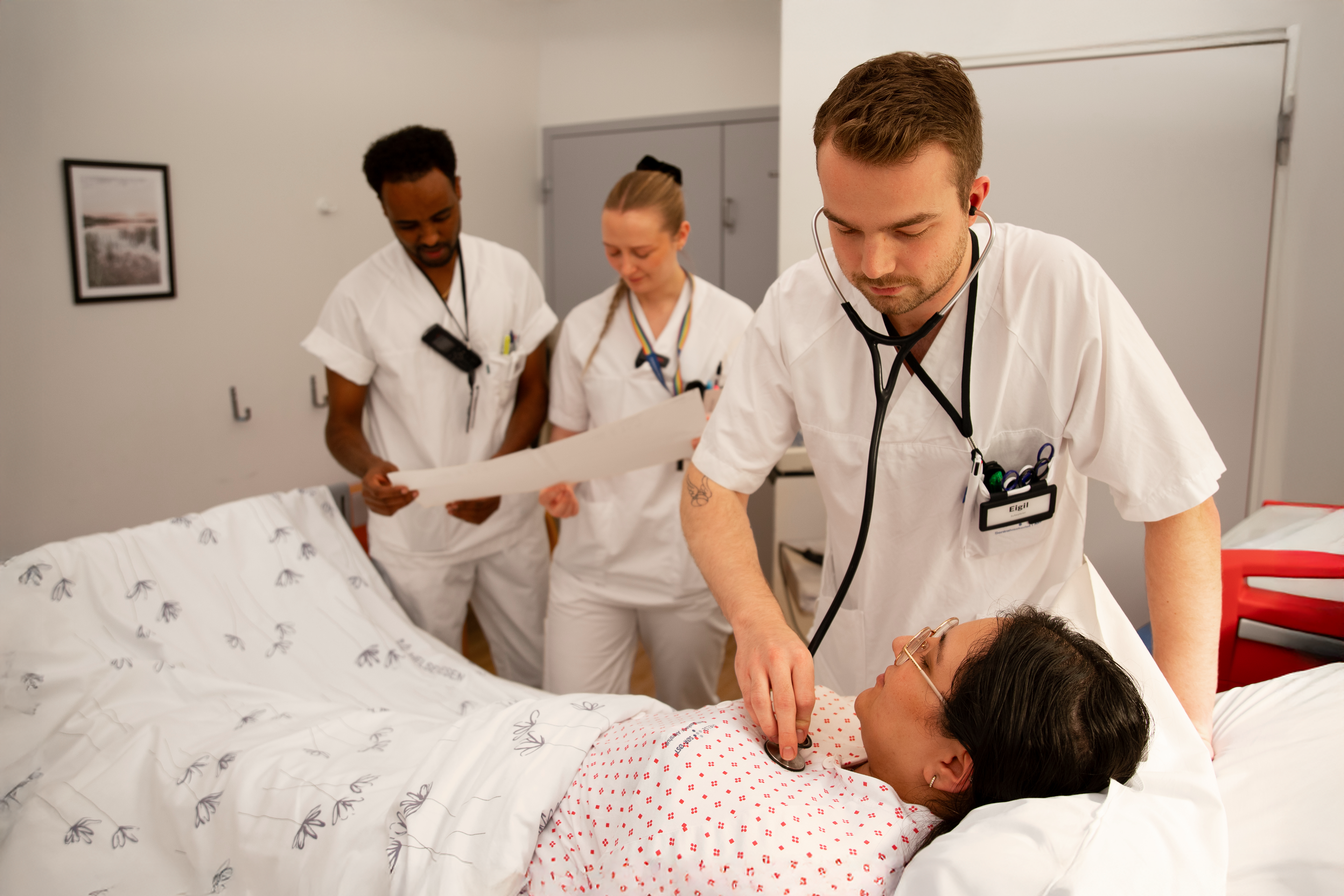 Helsepersonell behandler pasient i seng