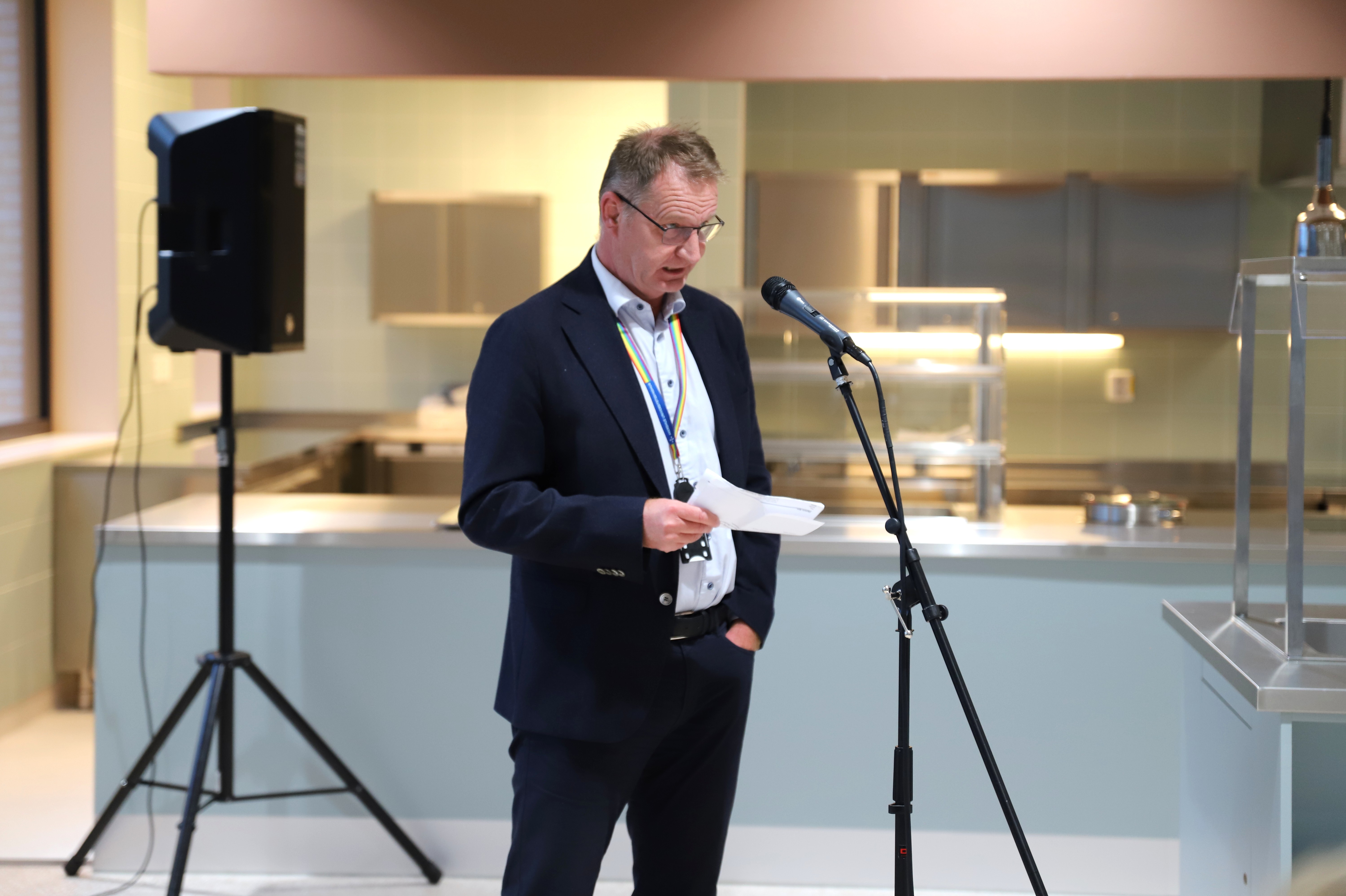 En mann som holder et papir og står foran en mikrofon