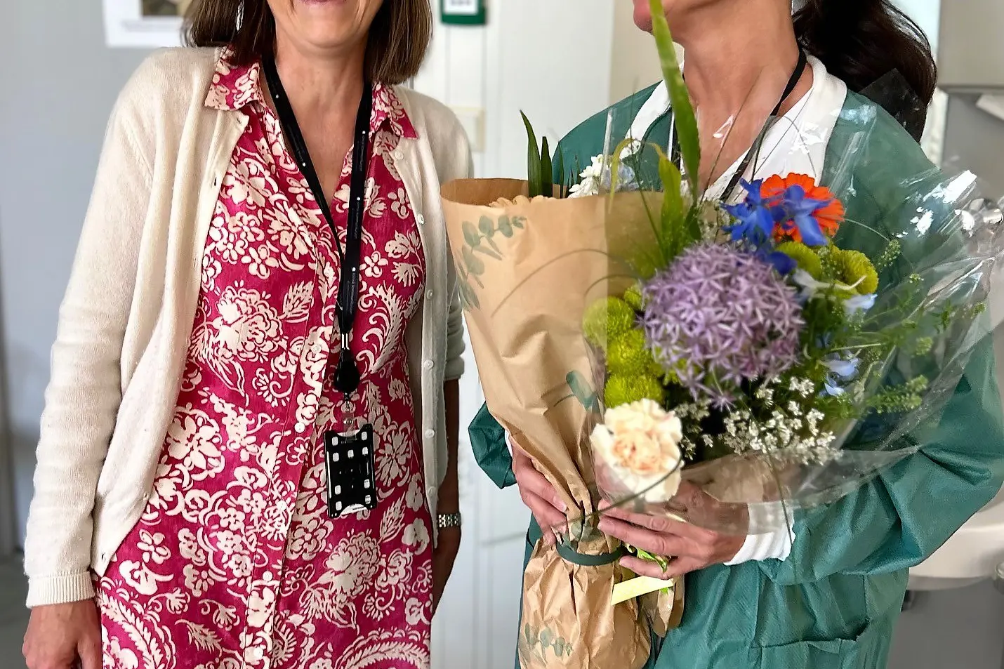 To kvinner side om side med smil og blomster